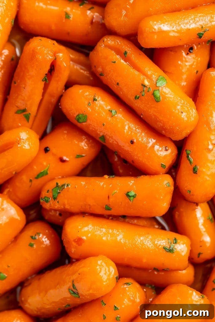 Close-up shot of glistening, tender candied carrots in a pan, highlighting their sweet glaze and vibrant color