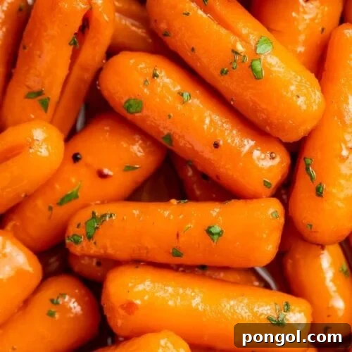 Close-up of candied carrots glistening with a sweet sauce in a serving dish