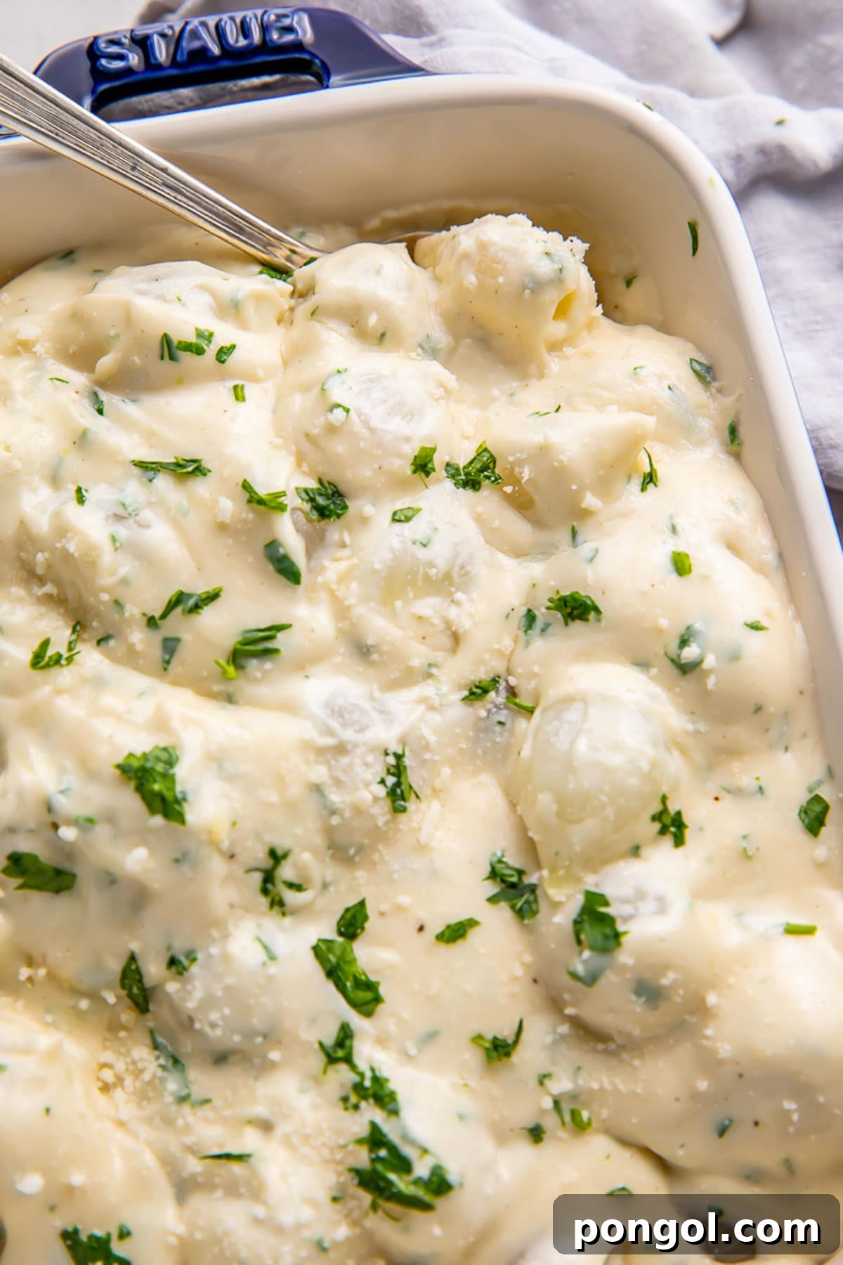 Velvety Creamed Onions 2 Creamed onions garnished with fresh herbs in a casserole dish.