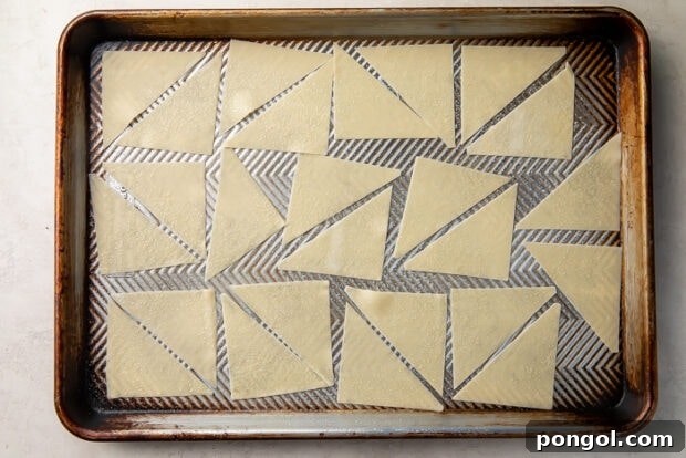 Wonton wrappers cut into triangles and arranged on a baking sheet