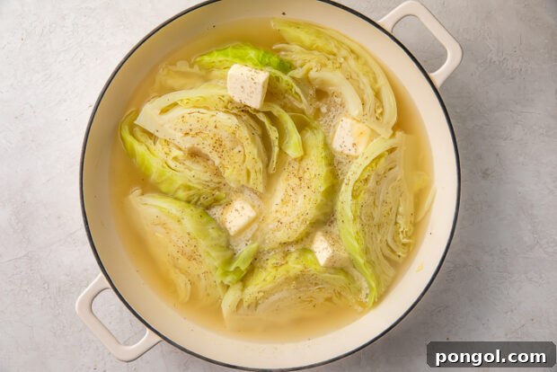 Cooked cabbage wedges with butter melting on top in a pot