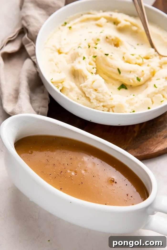 Rich brown gravy served in an elegant gravy boat, alongside a bowl of freshly made mashed potatoes