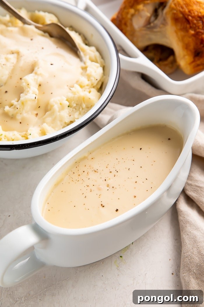 Gravy boat filled with chicken gravy next to a bowl of mashed potatoes