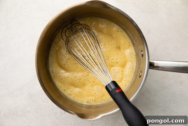 Step 2: Gradually whisking in chicken stock and bringing the gravy to a simmer.
