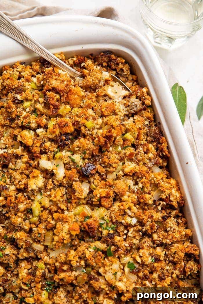 Heirloom Sausage Stuffing 2 Classic Sausage Stuffing in a white baking dish with a spoon, ready for serving.