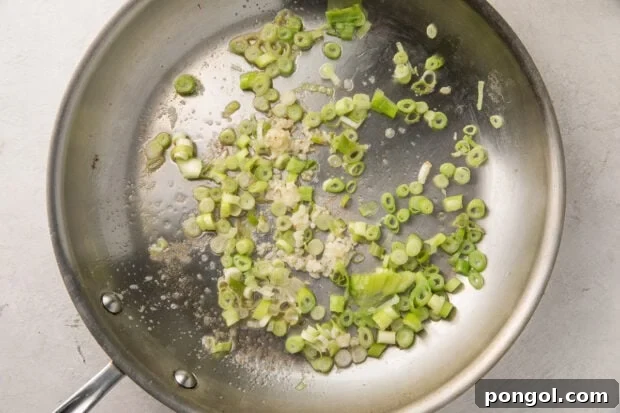 Garlic and green onion sauteed in a silver saucepan