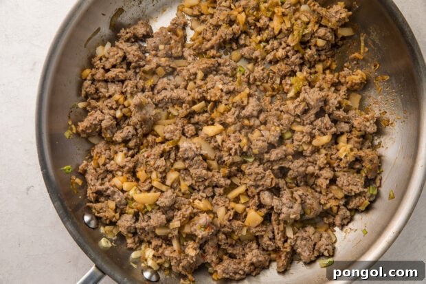 Ground pork, ginger, water chestnuts, and sriracha in a silver saucepan