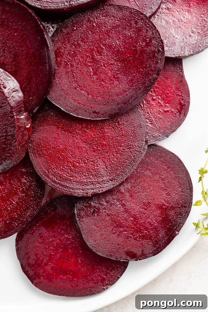 Dark red beets cut into medallions displayed on a white dish, ready to be served.
