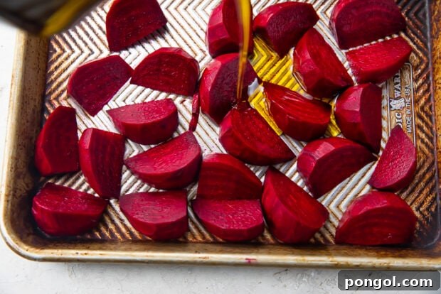 Dark red beet wedges covered with extra virgin olive oil on silver sheet pan