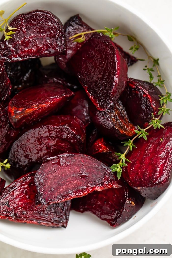 Deep red beets with green garnish in a white bowl, freshly roasted and ready to eat.