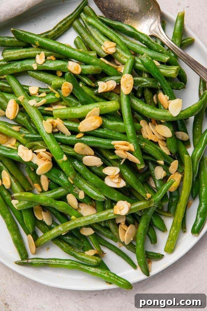 Green beans with almonds on a white platter, ready to be served.