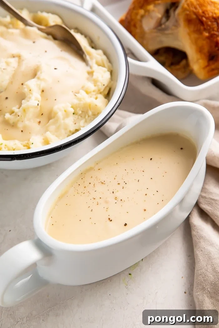 Gravy boat filled with chicken gravy next to a bowl of mashed potatoes