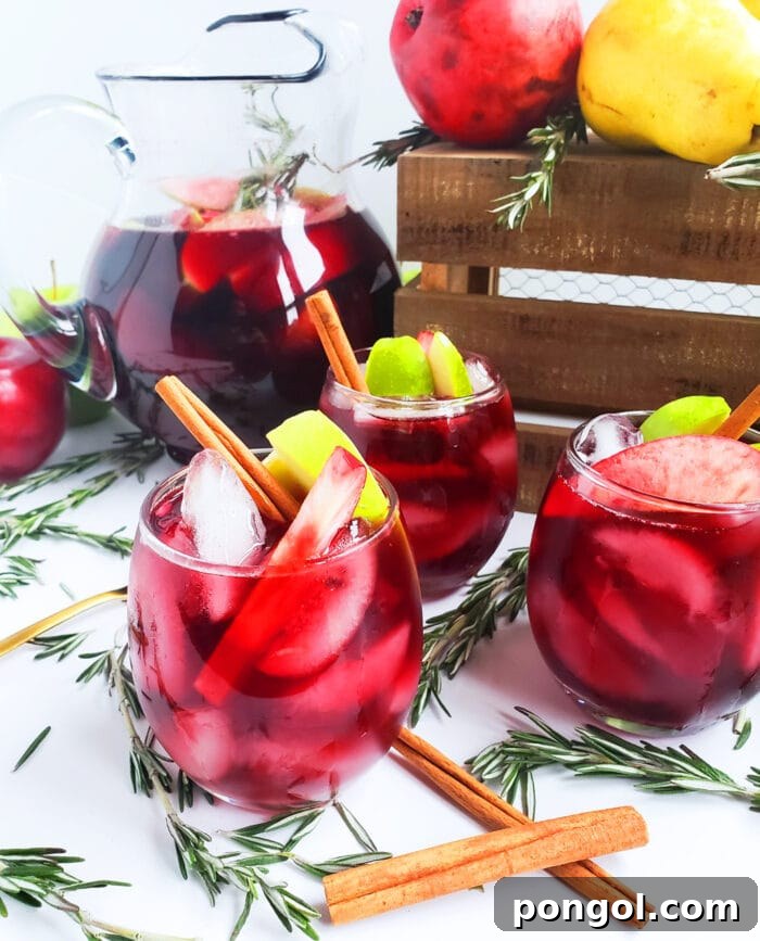 Red harvest sangria in stemless glasses with apples and cinnamon sticks