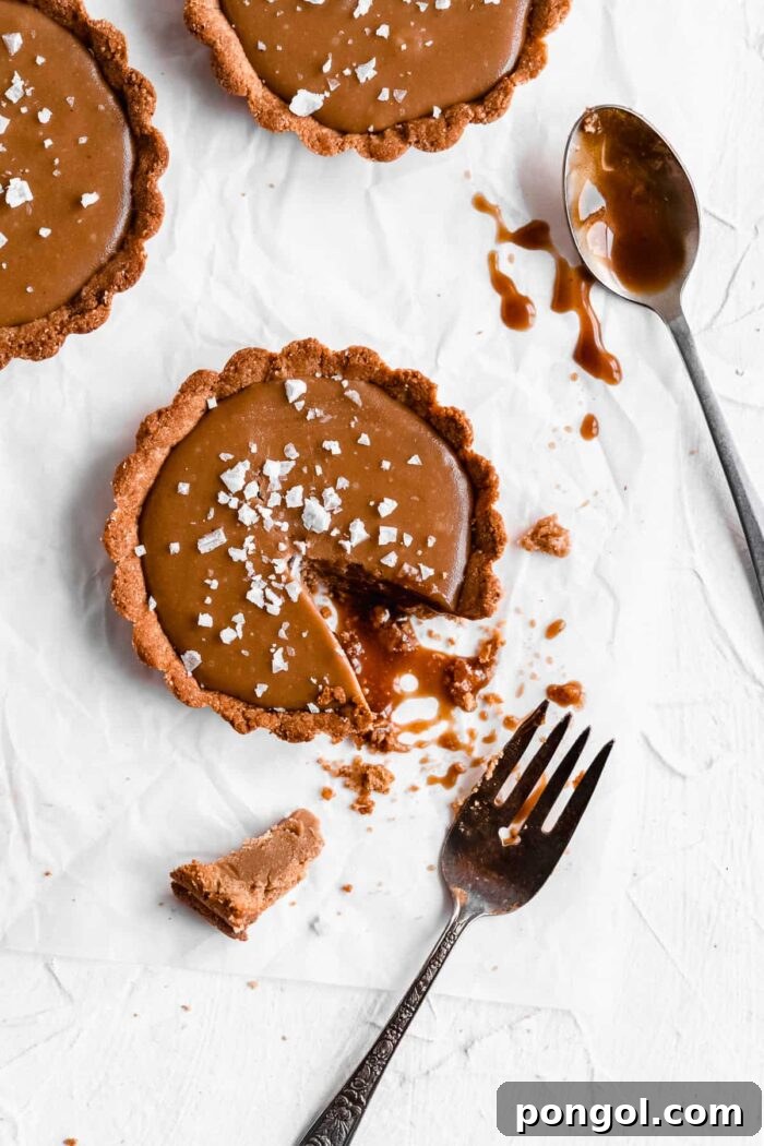 Salted caramel tart with missing piece and crumbs on a marble countertop