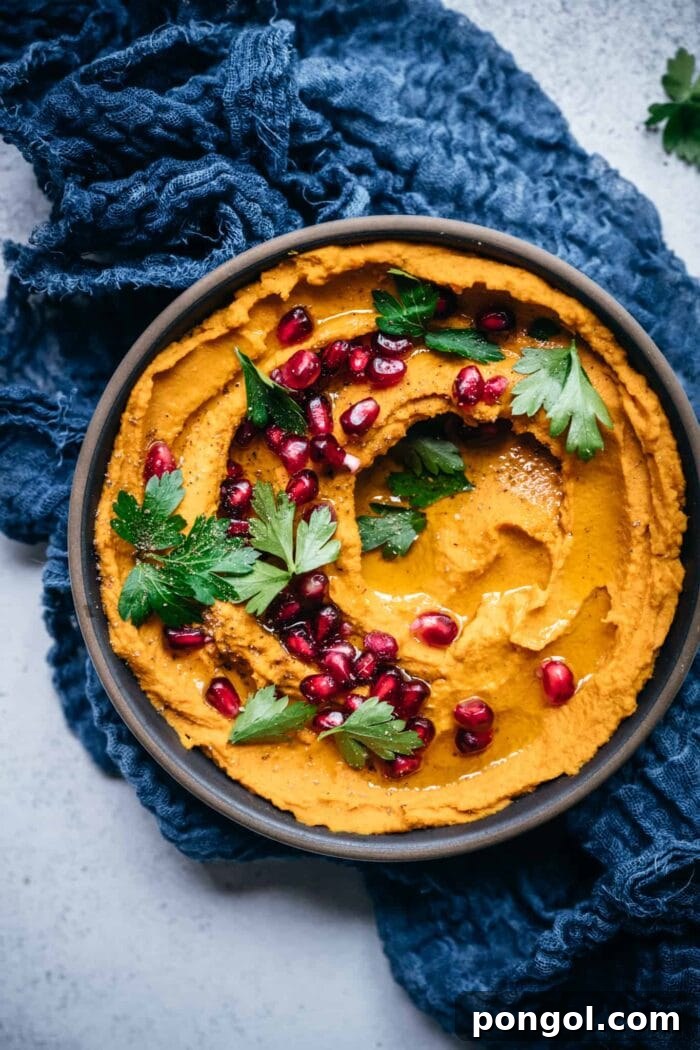 Black cast iron dish with roasted carrot dip, cranberries, and parsley