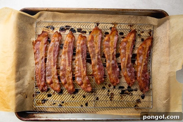 Crispy cooked bacon strips on a baking sheet after being removed from the oven