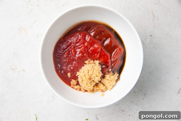 Ketchup, horseradish, and other ingredients for shrimp cocktail sauce in a white bowl on a marble countertop
