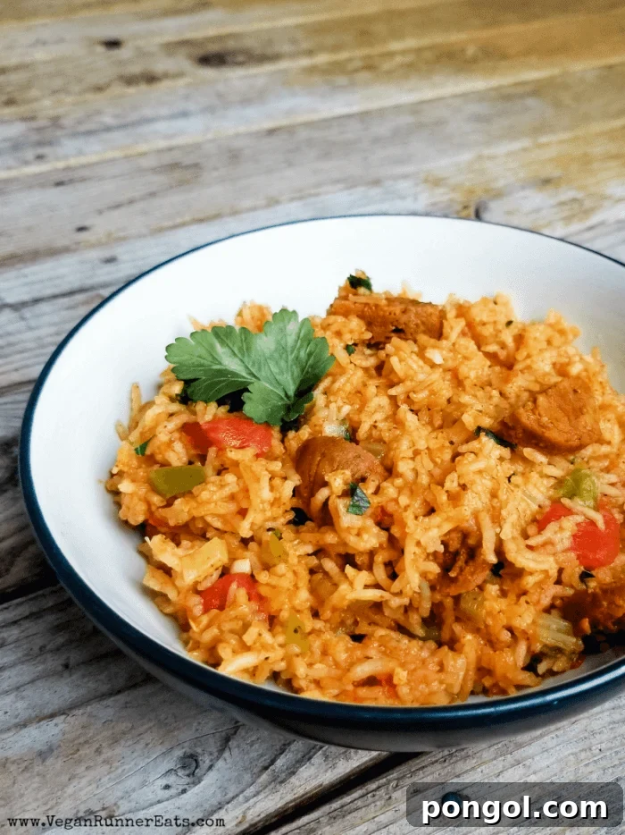 Vegetarian jambalaya in a dark bowl with white interior on a wooden table