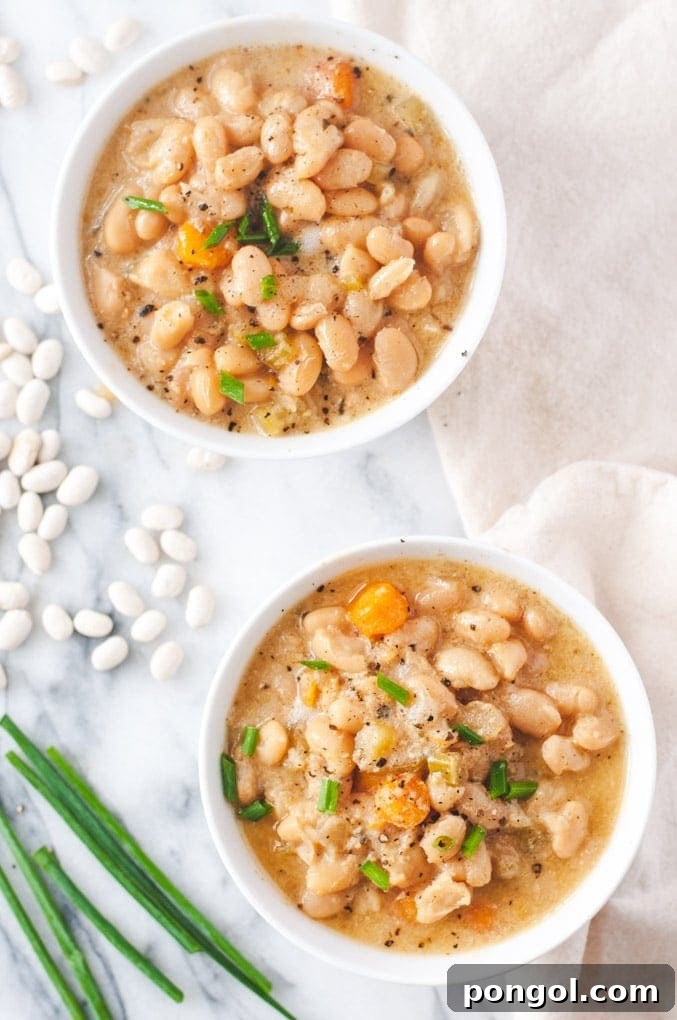 Two white bowls of vegetarian Instant Pot white bean soup with veggies