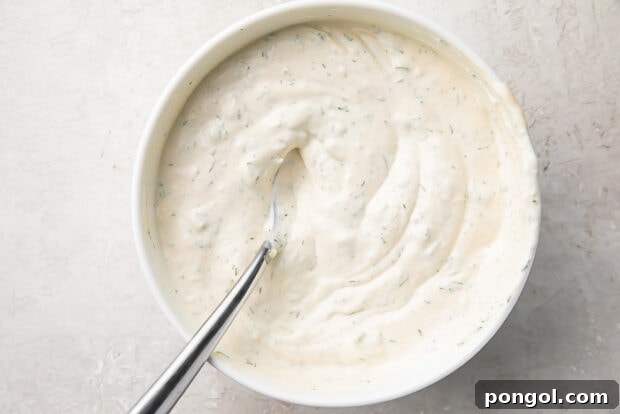 Finished horseradish sauce in a white bowl with a silver spoon, chilled and ready to serve.