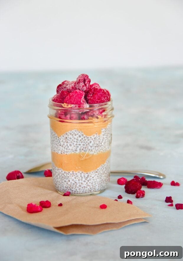 Peanut Butter & Jelly Chia Seed Pudding in a glass jar, topped with fresh raspberries.