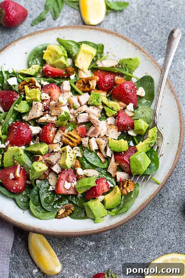 New Year, New You: 65 Satisfying Whole30 Meals 20 A refreshing strawberry avocado spinach salad presented on a white plate with a fork.