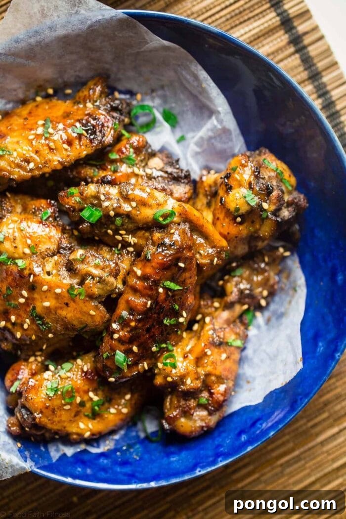 New Year, New You: 65 Satisfying Whole30 Meals 41 A blue ceramic bowl on a bamboo placemat holds glazed chicken wings, garnished with green onions.