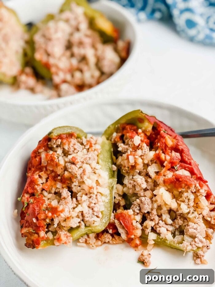 New Year, New You: 65 Satisfying Whole30 Meals 51 Pork and cauliflower rice stuffed peppers, neatly presented on a white plate.