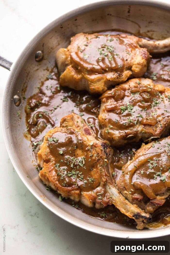 New Year, New You: 65 Satisfying Whole30 Meals 53 Balsamic mustard pork chops cooking in a brown skillet on a clean white background.