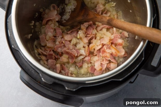 Onion, garlic, and bacon sautéing in an Instant Pot, releasing their aromas and building flavor.