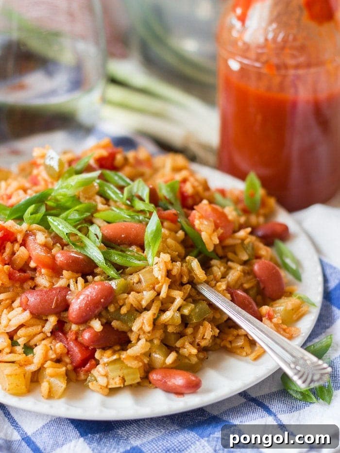 A plate of vegetarian slow cooker jambalaya with a fork on a blue and white tablecloth