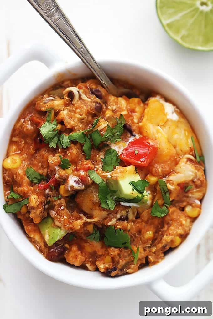 A white bowl of vegetarian slow cooker enchilada quinoa with a spoon