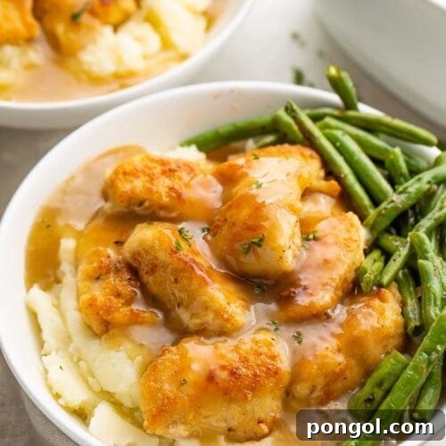 The ultimate Whole30 fried chicken and mashed potatoes with gravy and green beans in a white ceramic bowl, showcasing the entire meal.
