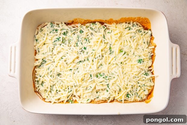 The Keto Lasagna Revelation 10 Baking dish showcasing layers of keto lasagna: meat sauce, egg thins, spinach and ricotta cheese mixture, and a generous sprinkle of mozzarella.
