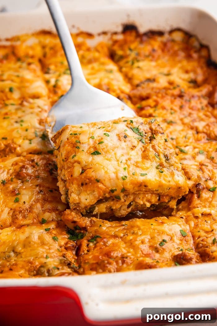 The Keto Lasagna Revelation 3 A large slice of rich keto lasagna being carefully lifted from a white casserole dish with a spatula, showcasing its decadent layers.
