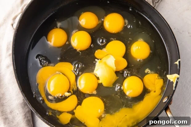 A dozen cracked eggs and ghee in a deep saucepan