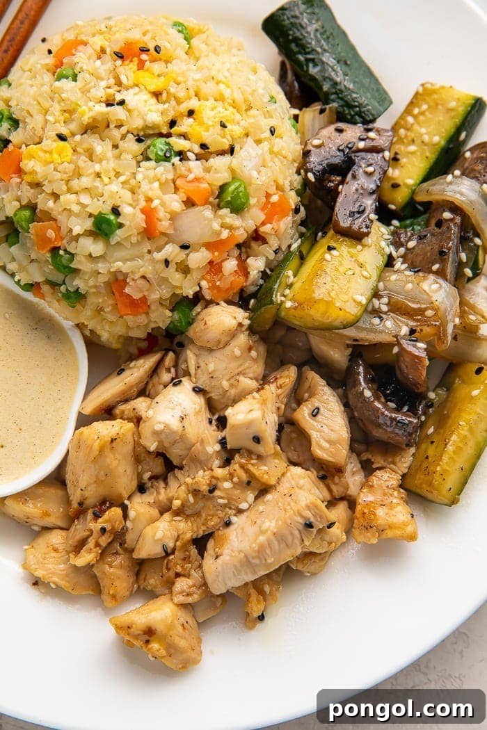 Close up photo of whole30 hibachi chicken, rice, and veggies on a white plate