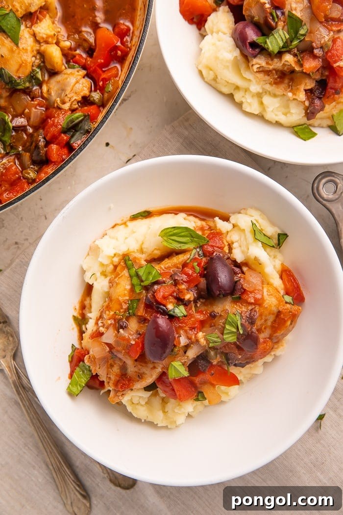 Plated Whole30 chicken cacciatore on top of mashed potatoes, garnished with basil
