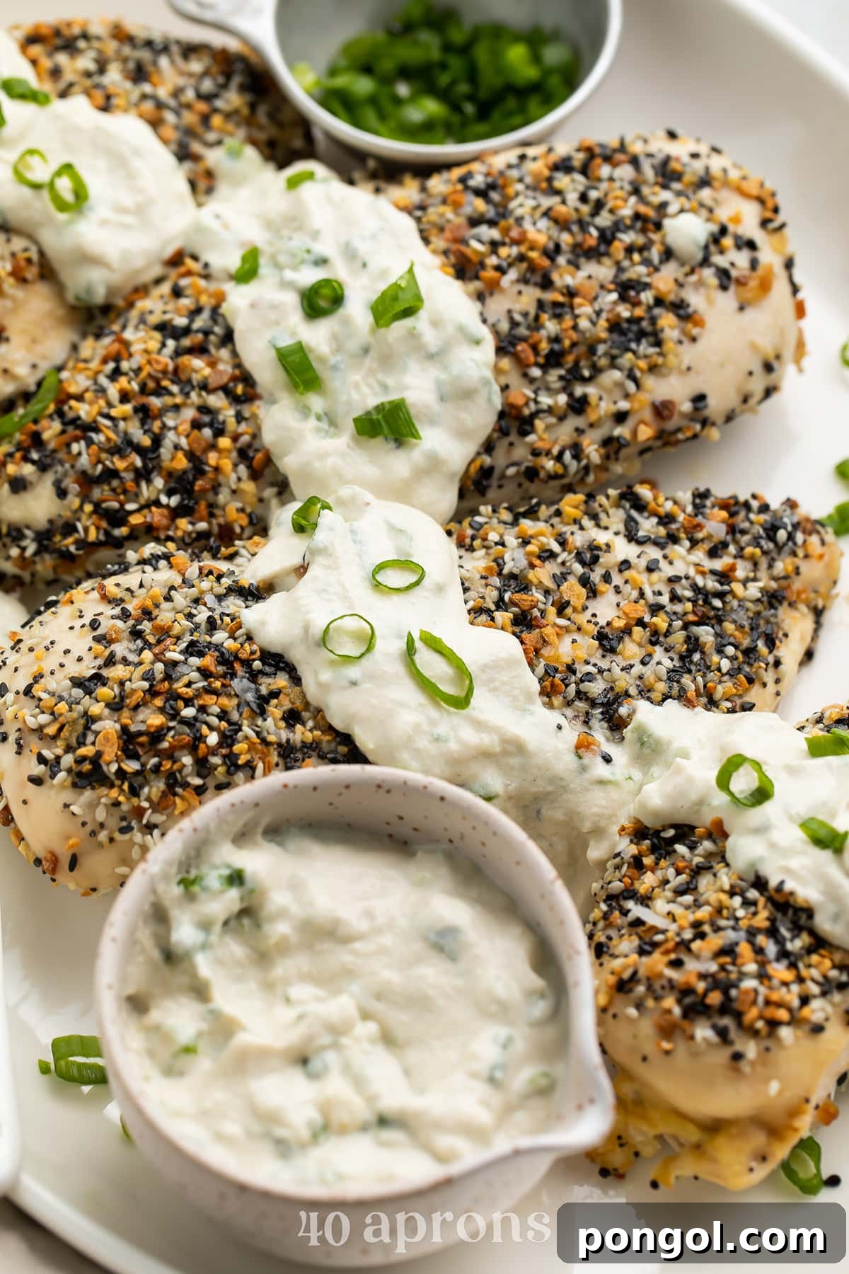Whole30 Everything Bagel chicken with a dairy-free scallion "cream cheese" sauce on a white oval platter.