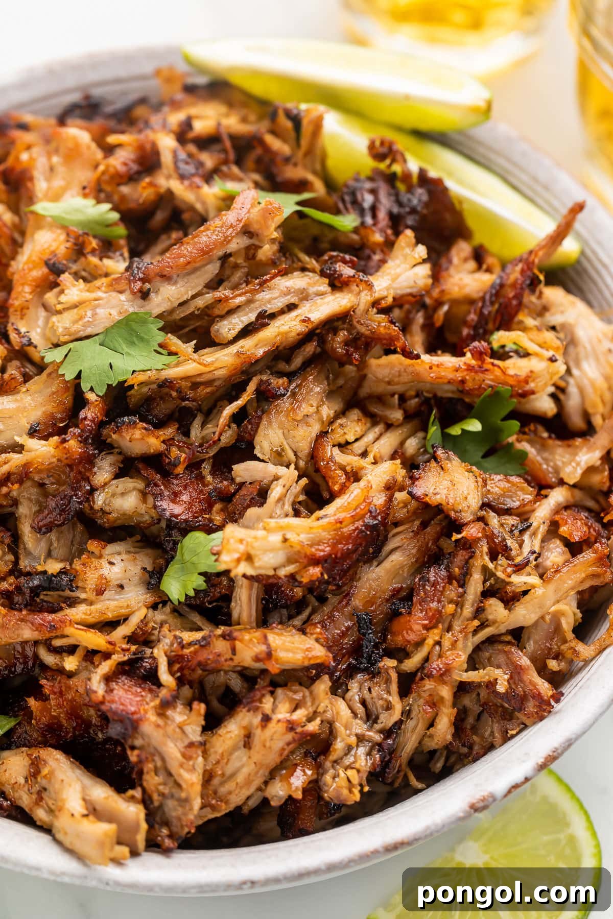 A bowl of slow cooker pork carnitas on a table.