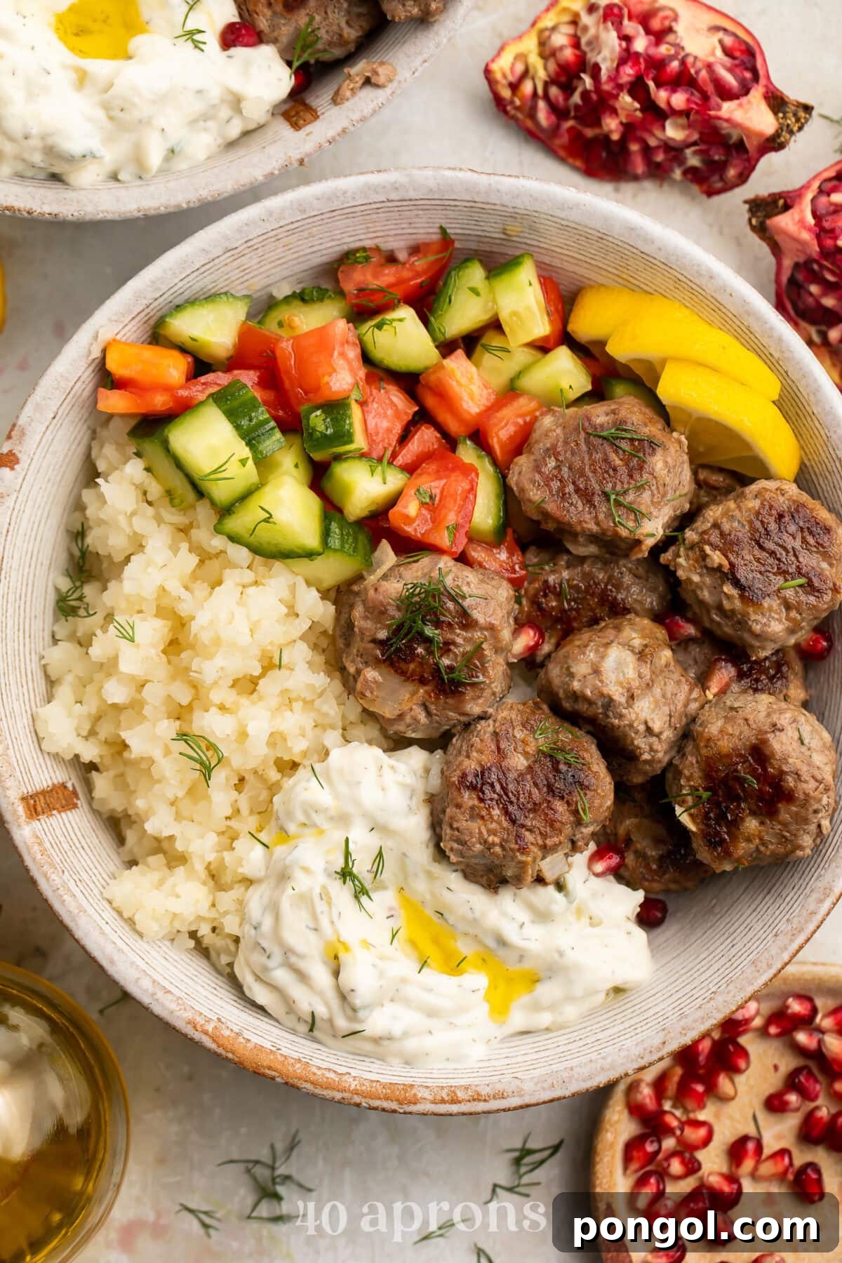 Whole30 gyro meatballs in a large bowl with tabbouleh, cucumber salsa, cauliflower rice, and Whole30 tzatziki.