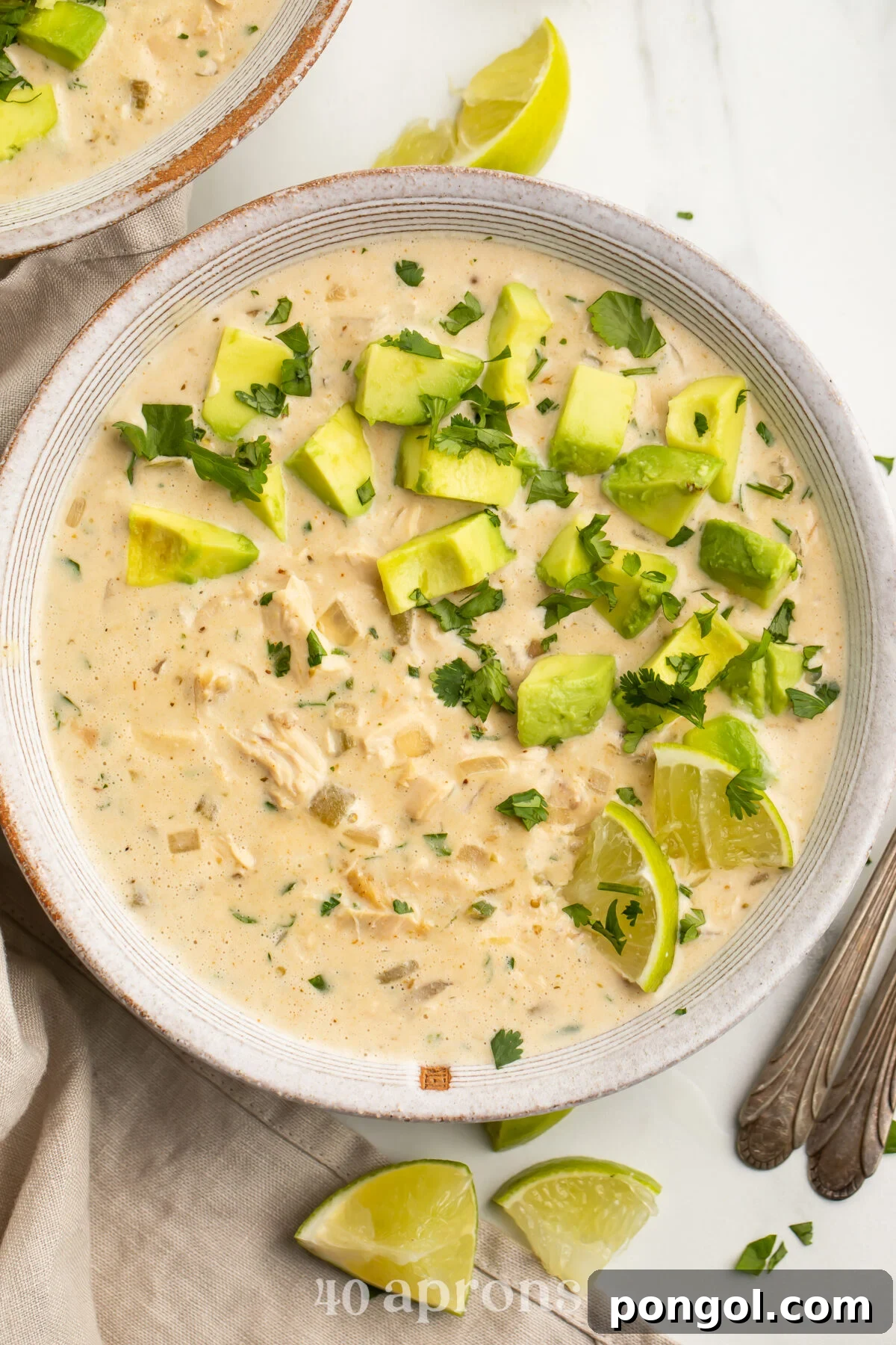 Top-down view of a bowl of Whole30-compliant white chicken chili topped with avocado and cilantro..