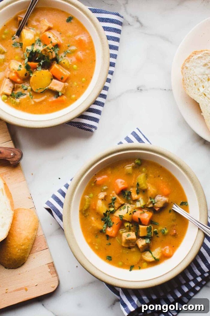 Comforting tofu and potato stew served in pristine white bowls, resting on striped napkins atop a clean white countertop.
