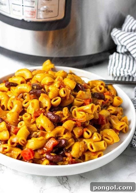 A rustic bowl filled with cheesy vegan chili mac and cheese, positioned invitingly in front of an Instant Pot.