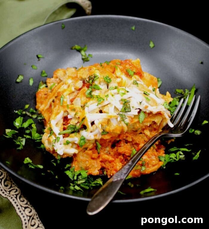 A perfectly portioned square of vegan lasagna, rich with layers of pasta and plant-based cheese, served in a large black bowl with a fork.