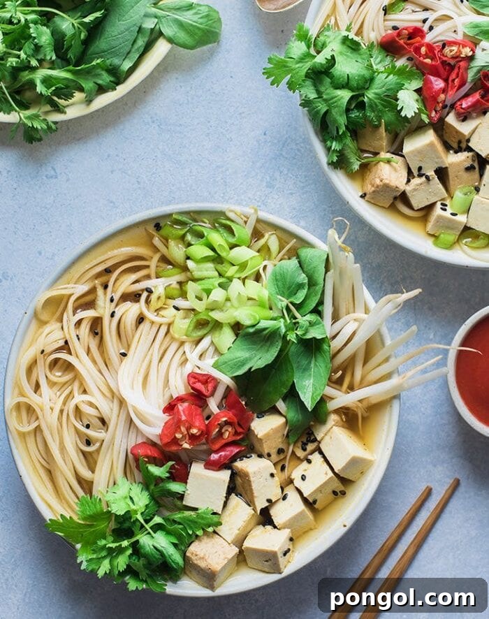 A pristine white bowl filled with aromatic vegan Instant Pot pho, positioned on a vibrant blue background amidst other accompanying bowls.