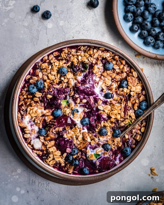 A warm, inviting brown bowl filled with vegan Instant Pot nectarine berry crisp, presented deliciously on a grey table.