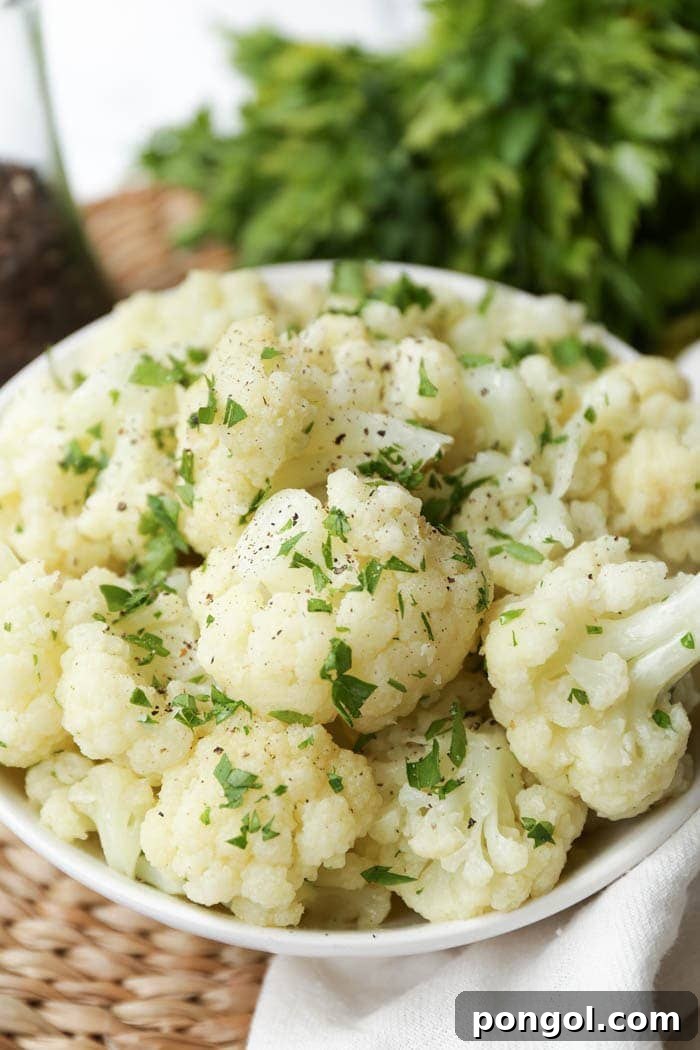 A white bowl brimming with tender cauliflower florets, lightly seasoned and garnished for a simple yet elegant side.