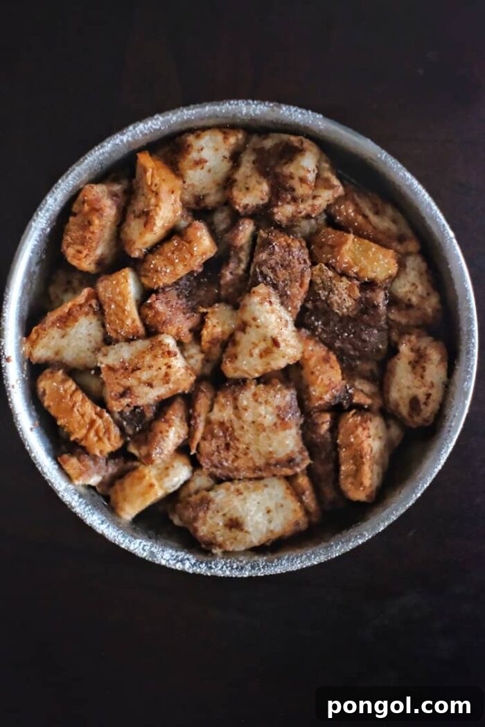 A warm, inviting bowl of French toast casserole, baked to golden perfection and presented against a dark, rustic background.