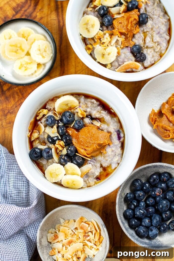 Two bowls of wholesome oatmeal, generously topped with plump blueberries, creamy peanut butter, and a drizzle of maple syrup.